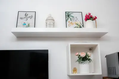 a fireplace with two white shelves with flowers on it at Staycation near Moa new room in Manila