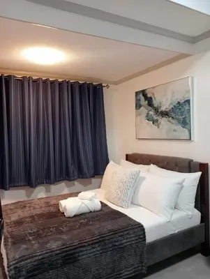 a bedroom with a large bed with white pillows at Downtown Makati Malls and Bars at your doorsteps in Manila