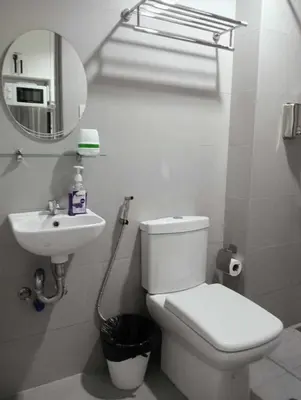 a bathroom with a toilet and a sink and a mirror at Downtown Makati Malls and Bars at your doorsteps in Manila