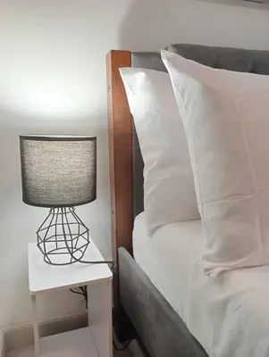 a lamp on a night stand next to a bed at Downtown Makati Malls and Bars at your doorsteps in Manila