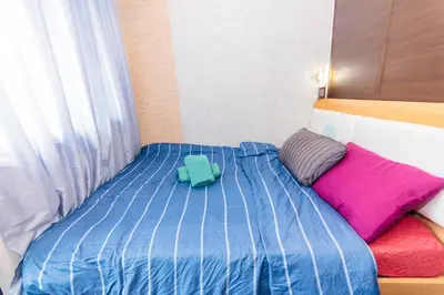 a bed with a blue comforter and colorful pillows at Eccentric Escape Stylish Makati Urban Swim Gym 4034 in Manila