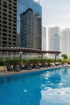 a large swimming pool with chairs and buildings at Tranquil Greenbelt Makati Condo - Free Pool Access in Manila