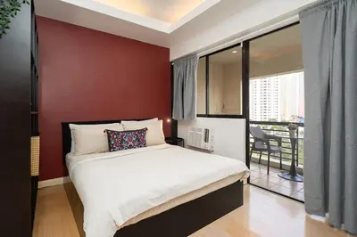 a bedroom with a bed with a red wall at Tranquil Greenbelt Makati Condo - Free Pool Access in Manila
