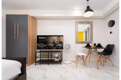 a bedroom with a tv and a table with chairs at Greenbelt Makati Condo with Balcony & Park Views in Manila