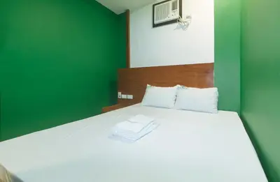 a bedroom with a white bed with a green wall at Ranchotel General Trias Cavite by RedDoorz in Uldugan