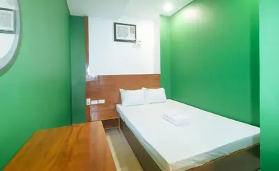 a small green room with a bed and a table at Ranchotel General Trias Cavite by RedDoorz in Uldugan