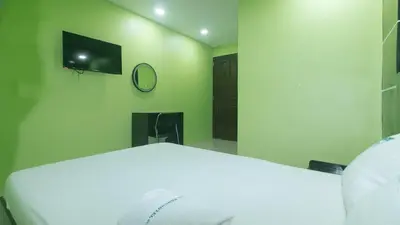 a bedroom with a white bed and a tv on the wall at Ranchotel General Trias Cavite by RedDoorz in Uldugan