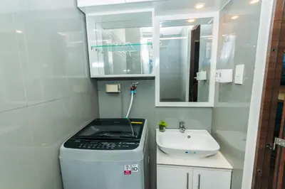 a small bathroom with a sink and a washing machine at Boutique Air Retreat Relax Laugh Swim Gym Car Park 1767 in Manila