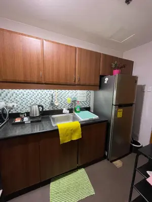 a kitchen with wooden cabinets and a stainless steel refrigerator at Resorts world condotel High speed wifi in Manila