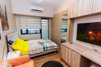 a bedroom with a bed and a flat screen tv at The Laughing Loft Cosmopolitan Comfort Gym Swim Park 2428 in Manila