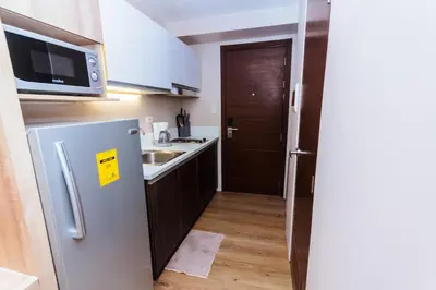 a small kitchen with a refrigerator and a sink at The Laughing Loft Cosmopolitan Comfort Gym Swim Park 2428 in Manila