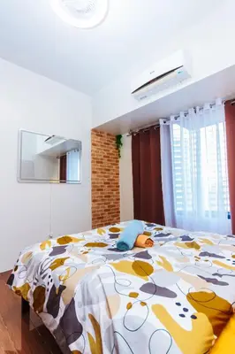 a bedroom with a large bed with a colorful blanket at Serene City Stay Trendy Cozy Makati Condo Fun Swim Gym Netflix 4047 in Manila