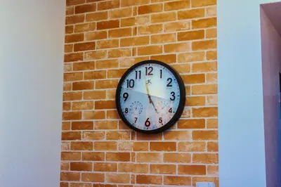 a clock on the side of a brick wall at Serene City Stay Trendy Cozy Makati Condo Fun Swim Gym Netflix 4047 in Manila