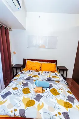 a bedroom with a bed with orange pillows at Serene City Stay Trendy Cozy Makati Condo Fun Swim Gym Netflix 4047 in Manila