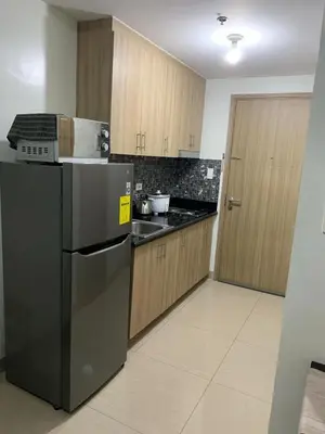 a kitchen with a black refrigerator and wooden cabinets at ren&ayesha place in Manila