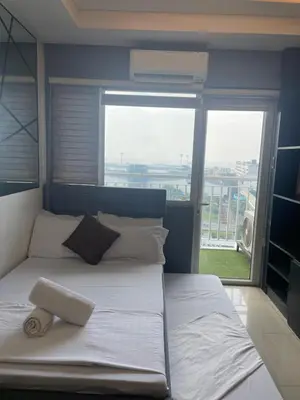 a large bed in a room with a large window at Mall of asia fireworks view from balcony 15floor in Manila