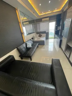 a living room with a black leather couch and a bed at Mall of asia fireworks view from balcony 15floor in Manila