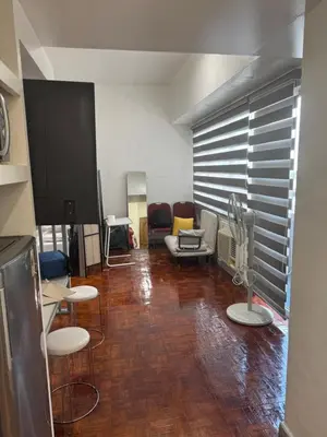 a living room with chairs and a tv in it at Greenhills shopping center studio condominium in Manila