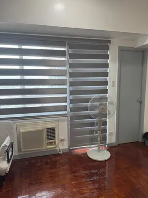 a room with a fan in front of a window at Greenhills shopping center studio condominium in Manila