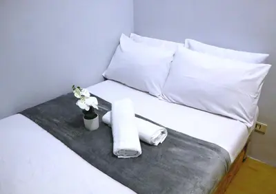 a bed with white pillows and a tray with towels at 2BR Condotel Ridgewood Tower Taguig in Manila
