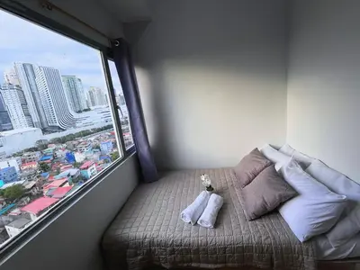 a bed in a room with a large window at 2BR Condotel Ridgewood Tower Taguig in Manila