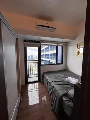 a bedroom with a bed and a large window at The Air Residences #3724 in Manila