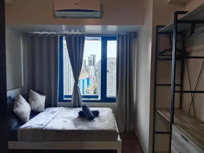 a bedroom with a bed and a large window at Cozy & Stylish Staycation and Netflix - WiFi and Pool in Manila