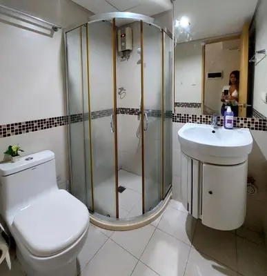 a bathroom with a shower and a toilet and a sink at Solemare Parksuites in Manila