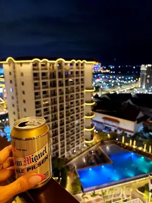 a person holding a can in front of a building at Solemare Parksuites in Manila