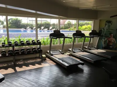 a row of treadmills in a gym with a window at Solemare Parksuites in Manila