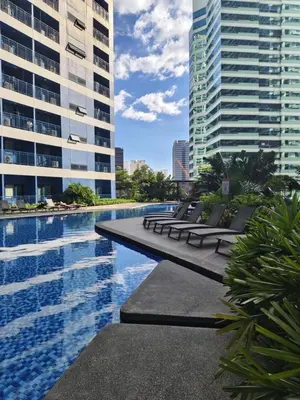 a swimming pool with lounge chairs and buildings at Air Residences by Christine Suites PH Makati City in Manila