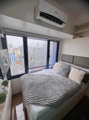 a bedroom with a bed and a large window at Air Residences by Christine Suites PH Makati City in Manila