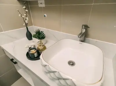a bathroom with a white sink and a vase with flowers at 5-Star Feel and Step in Luxury at Fame Residences in Manila