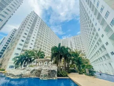 a hotel with palm trees in front of two tall buildings at Shore residence Tower D moa ecom view cozy bedroom in Manila