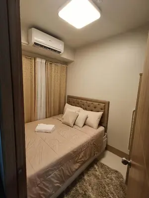 a small bedroom with a bed with a air conditioner at CLMN Staycation Metro Manila in Manila
