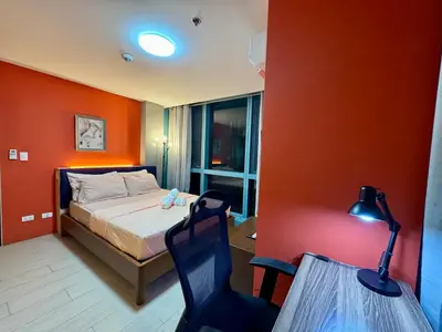 a bedroom with a bed with an orange wall at BGC One Uptown 2bedroom with balcony and 1 free parking in Manila