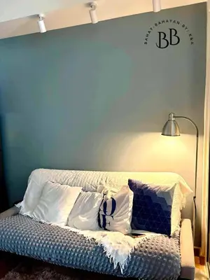 a blue wall with a bed with pillows and a lamp at Bahay-Bahayan by K&A at Azure Urban Resort Residences in Manila