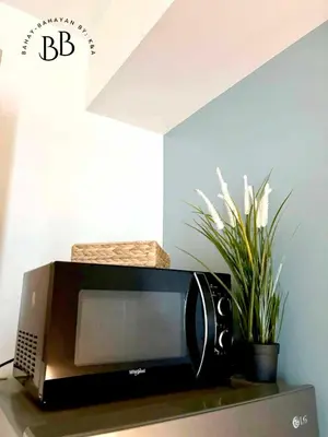 a microwave sitting on top of a table with a plant at Bahay-Bahayan by K&A at Azure Urban Resort Residences in Manila