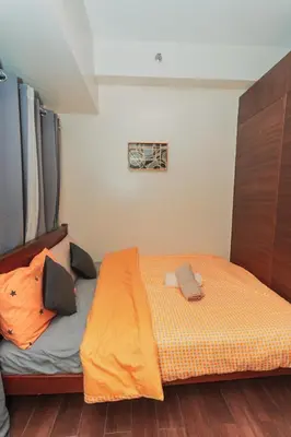 a small bedroom with a bed with an orange blanket at The Quirk Inn Air residence Makati Swim Gym Park Eat Laugh 3301 in Manila