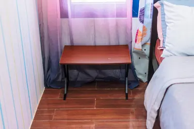 a small wooden table next to a bed in a room at Urban Hideaway Cozy Makati Giggles Swim Gym Park Laugh Eat 3352 in Manila