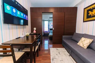 a living room with a couch and a table and a tv at Urban Hideaway Cozy Makati Giggles Swim Gym Park Laugh Eat 3352 in Manila