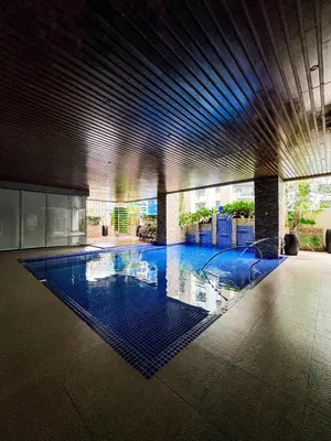 a large swimming pool in a building with blue lighting at Business Studio in Salcedo Village Makati in Manila