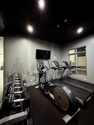 a gym with several tread machines and a flat screen tv at Business Studio in Salcedo Village Makati in Manila