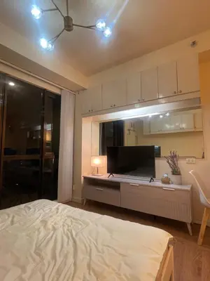 a bedroom with a bed and a kitchen with a tv at Grand Soho Makati Condo in Manila