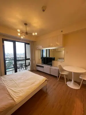 a bedroom with a bed and a table and a kitchen at Grand Soho Makati Condo in Manila