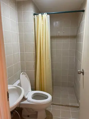 a bathroom with a toilet and a yellow shower curtain at Grand Soho Makati Condo in Manila
