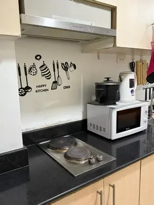 a kitchen with a microwave and a stove top oven at Sea Residences at Rose stayction in Manila