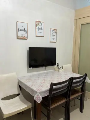a dining room with a table with chairs and a tv at Sea Residences at Rose stayction in Manila
