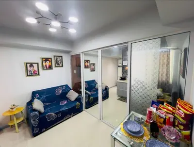 a living room with a blue couch and a mirror at Azure's Best by Condo Suites PH in Manila