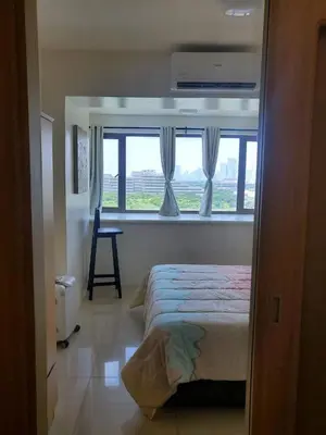 a bedroom with a bed and a window with a chair at Barkada Room by Metro Staycation in Manila